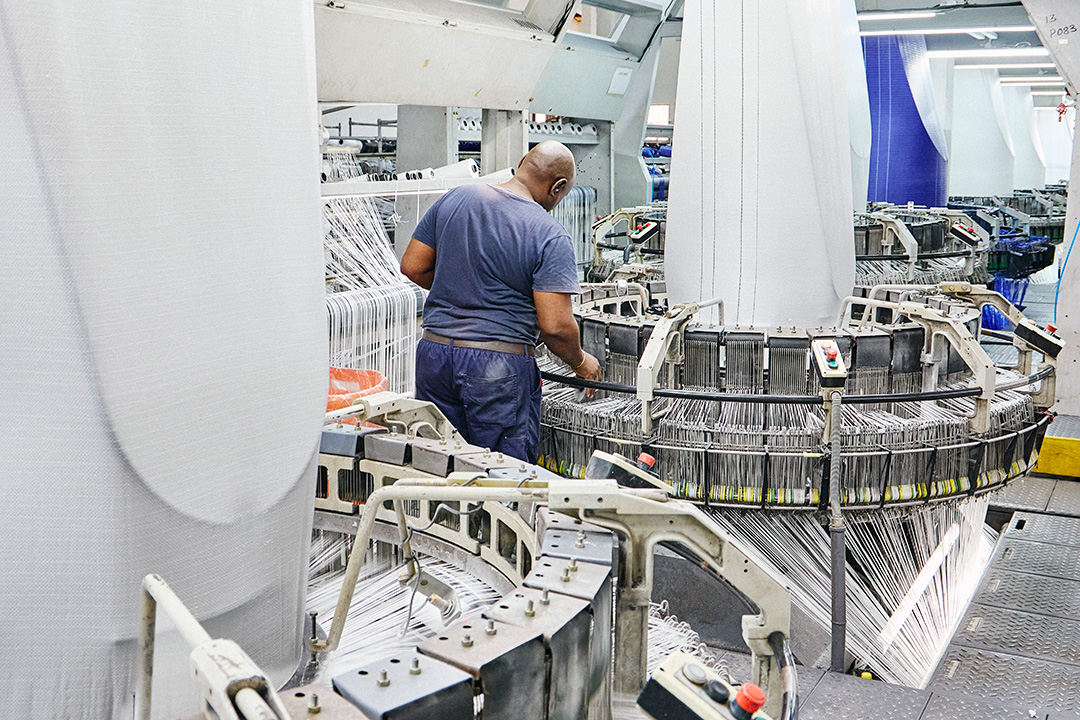 An IPP employee works on a weaving loom in the IPP factory.